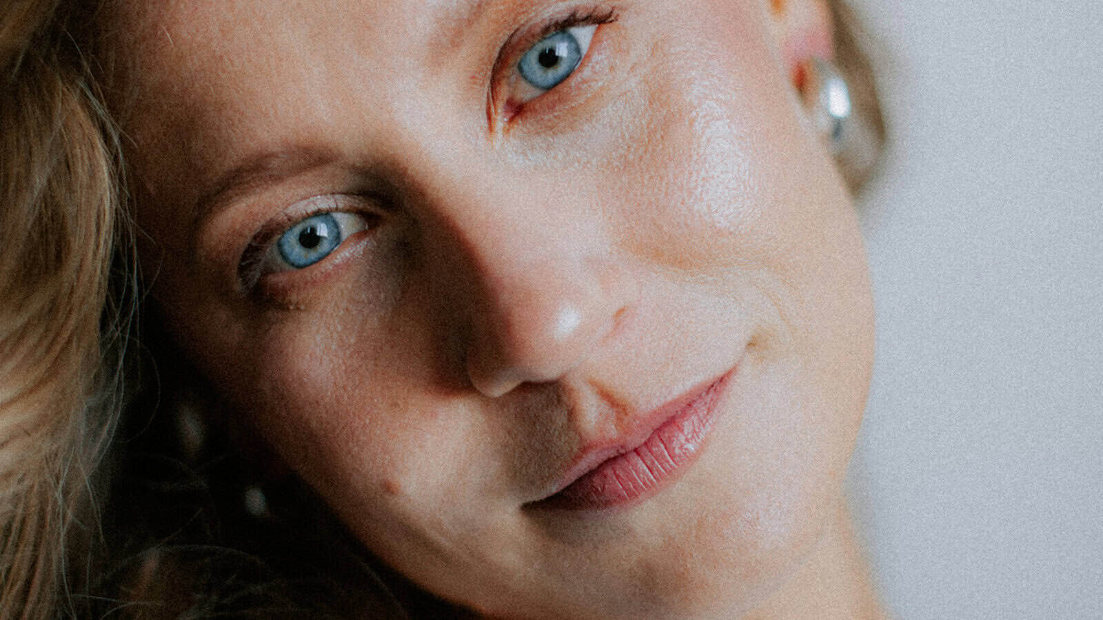Close-up portrait of a woman with blue eyes looking directly at the camera.
