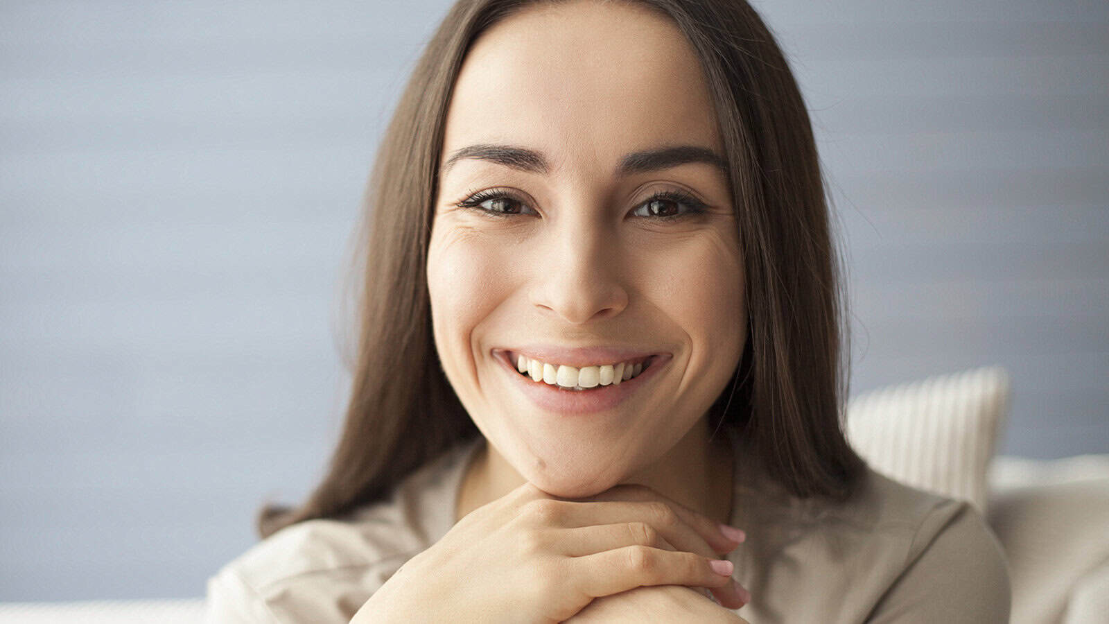 A smiling woman resting her chin on her hands.
