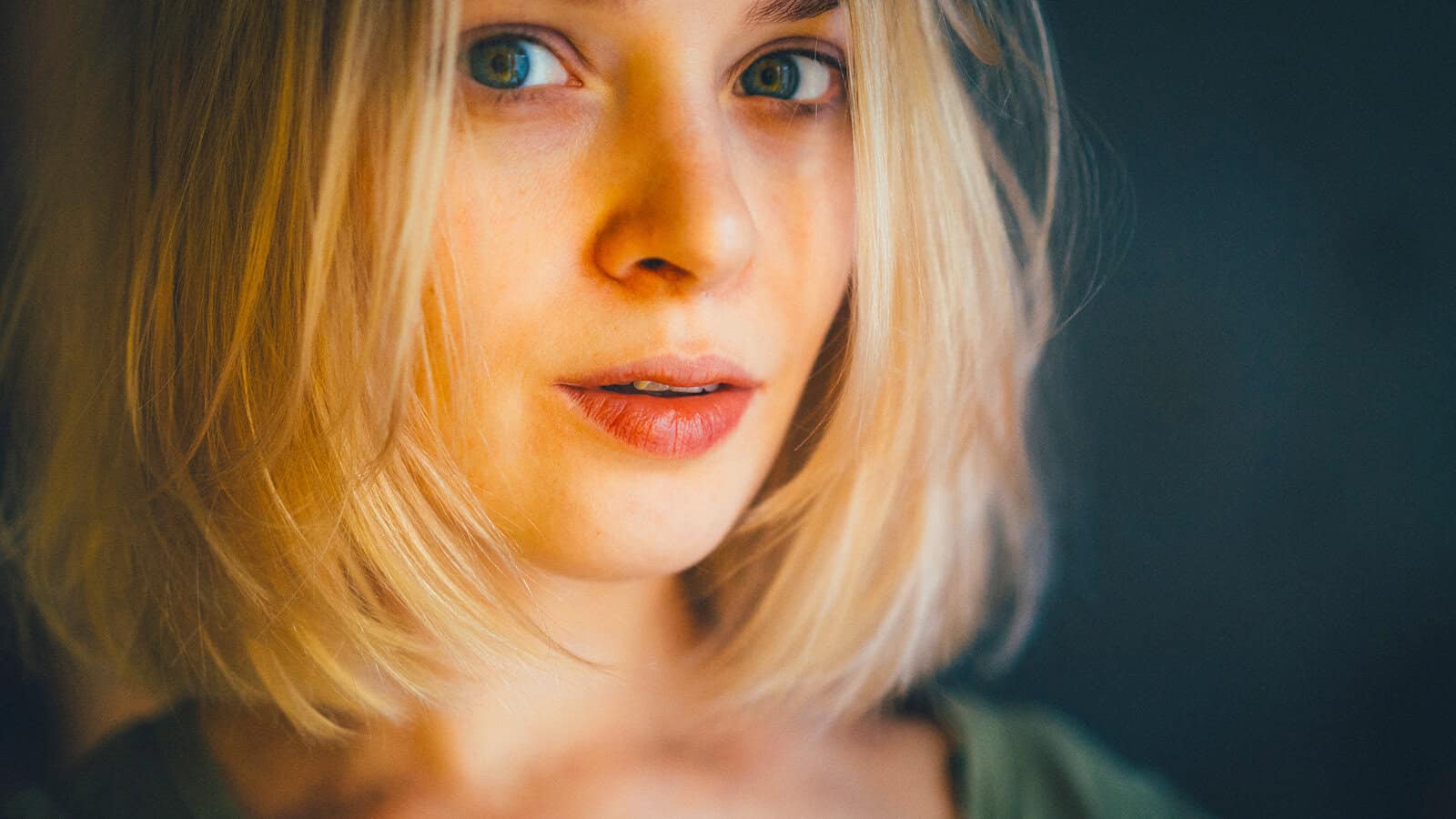 A close-up portrait of a woman with blonde hair looking directly at the camera.