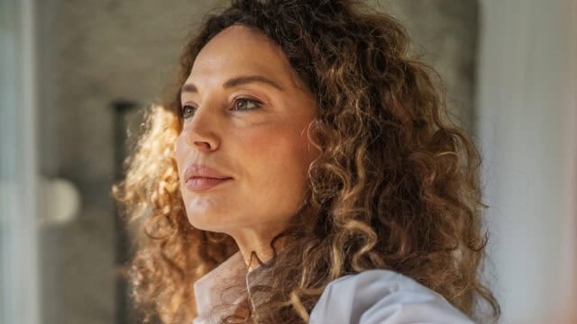 A woman with curly hair looking to the side.