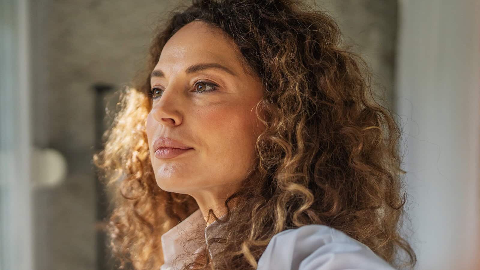A woman with curly hair looking to the side.