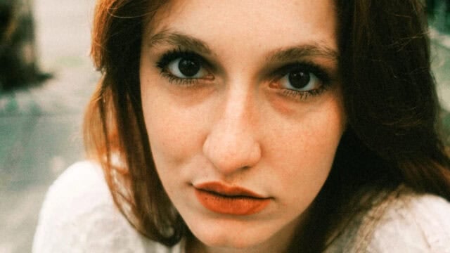Close-up portrait of a woman looking directly at the camera.