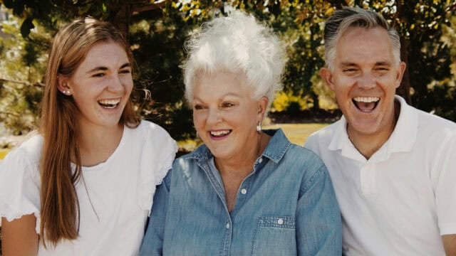Three people laughing together outdoors.