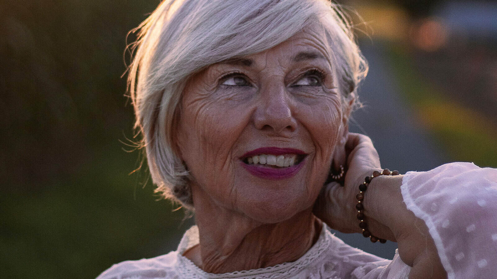 Close-up of a smiling older woman with short gray hair, looking upward.