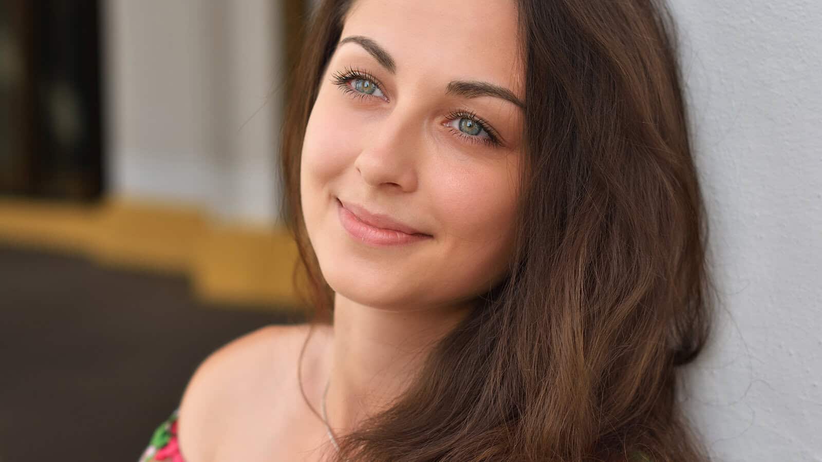 A woman with long brown hair smiling gently.