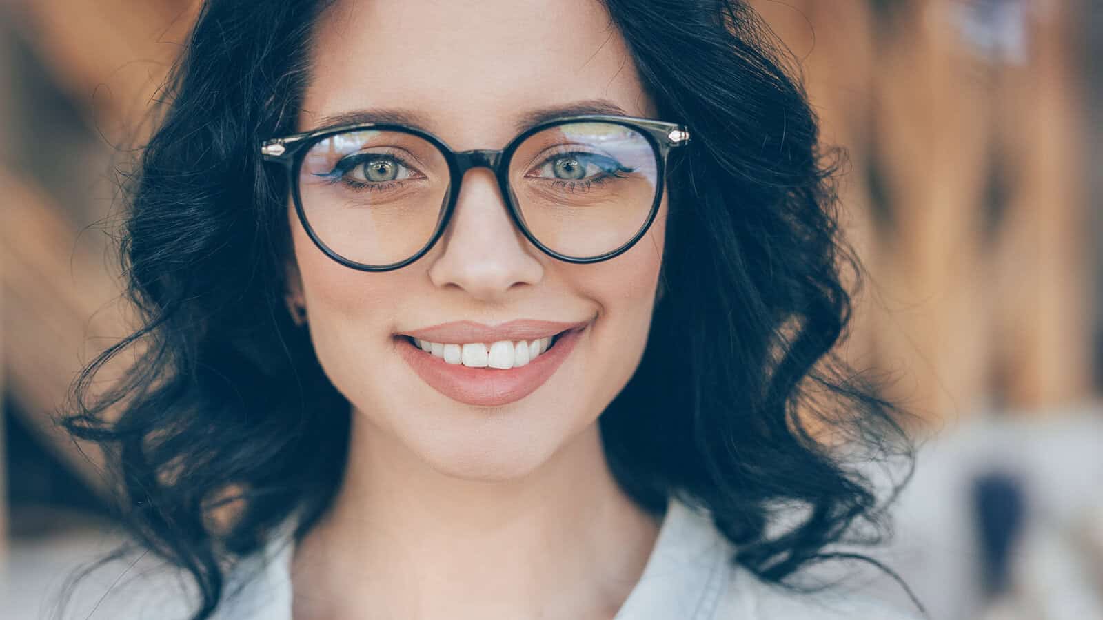 A smiling woman with dark hair wearing black-rimmed glasses.