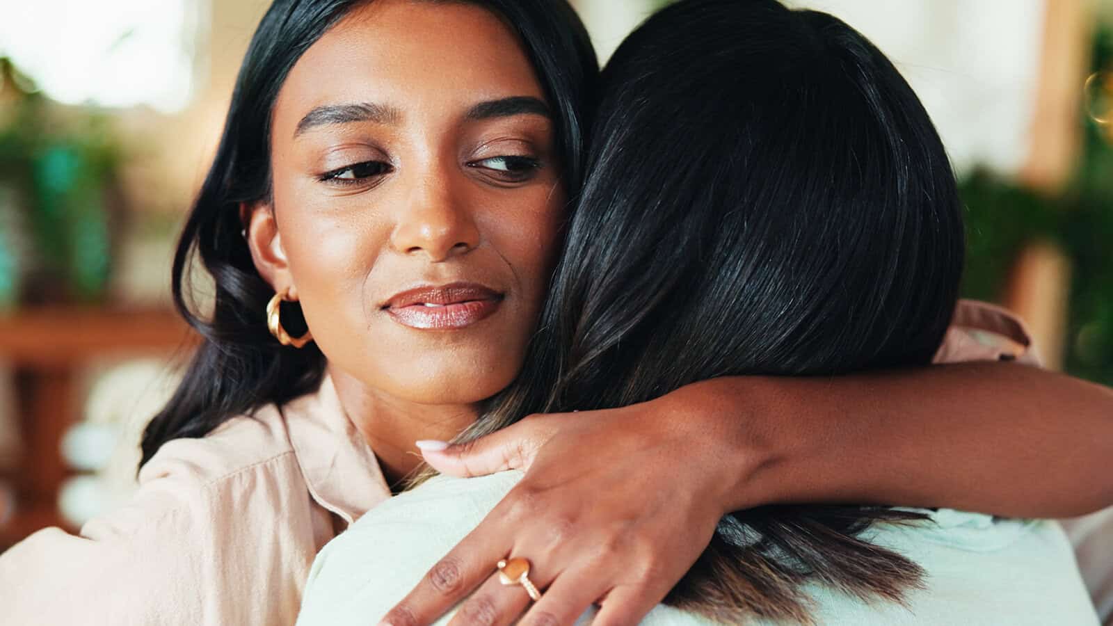 A woman with dark hair embraces another person.