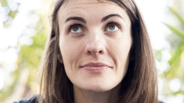 Close-up portrait of a woman looking upward with a thoughtful expression.