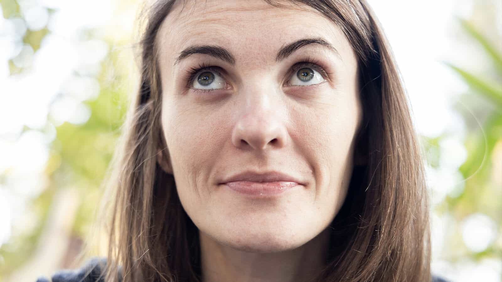 Close-up portrait of a woman looking upward with a thoughtful expression.