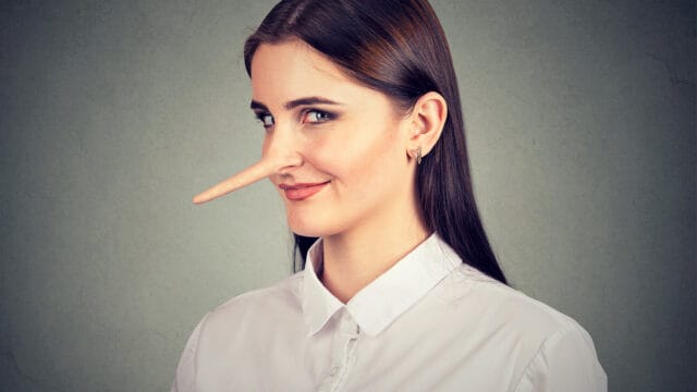 A woman with a long, wooden Pinocchio-style nose looking sideways with a smirk, illustrating the psychology of lying.