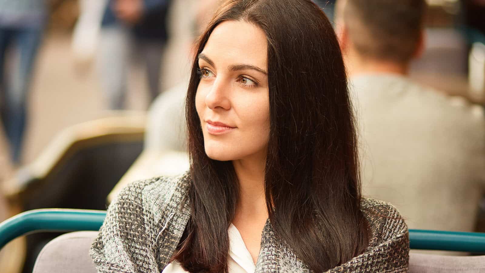 Photo of beautiful brunette woman focused aside, wrapped in coverlet, thinks about something with thoughtful expression