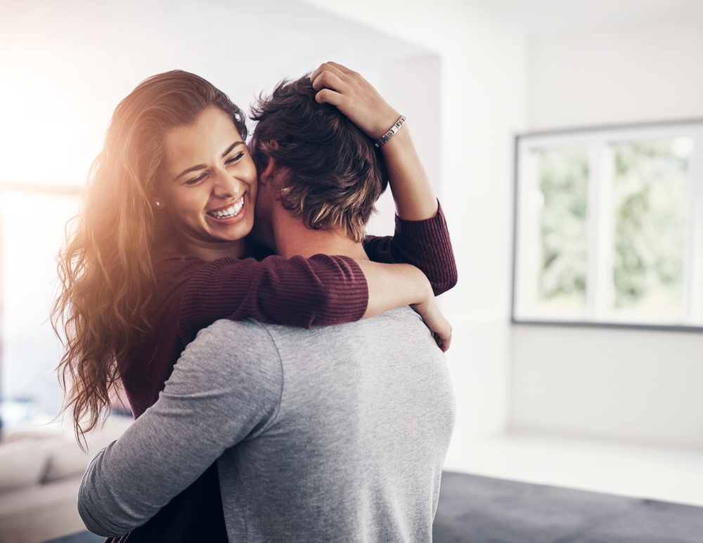 A young woman hugging her boyfriend tight