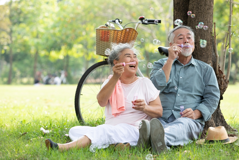 Senior couple blowing bubbles together at a park
