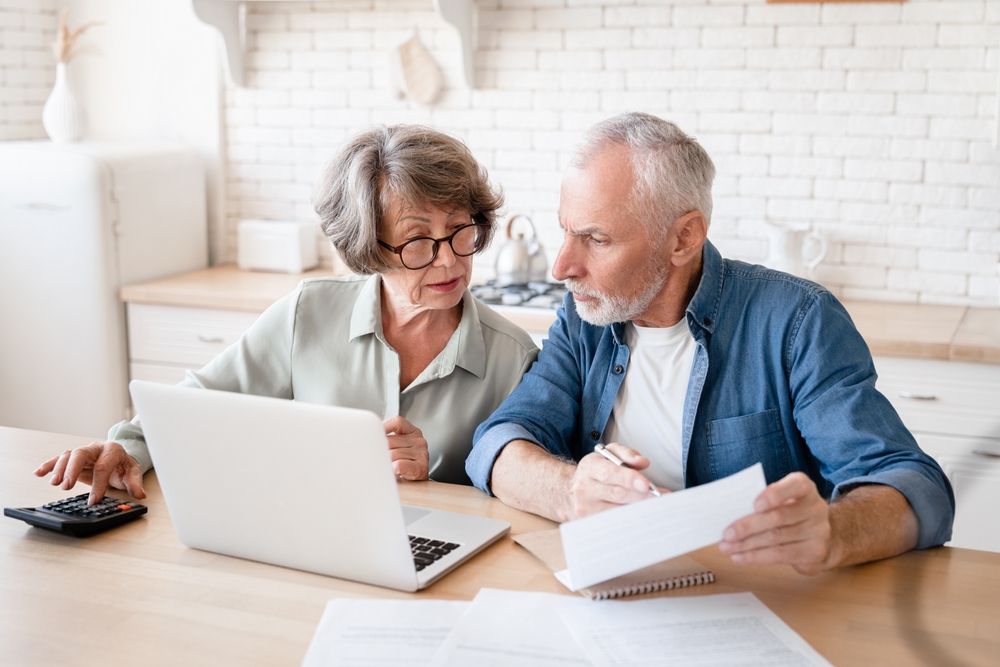A busy elderly senior couple working on their finances with their laptop