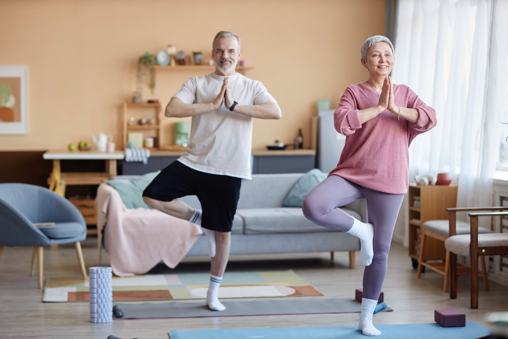 A senior couple doing yoga together in their living room