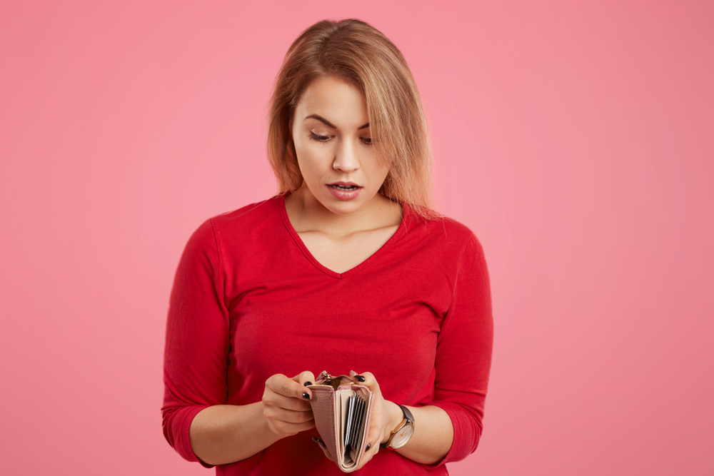 Broke woman staring into her wallet who is worried about money