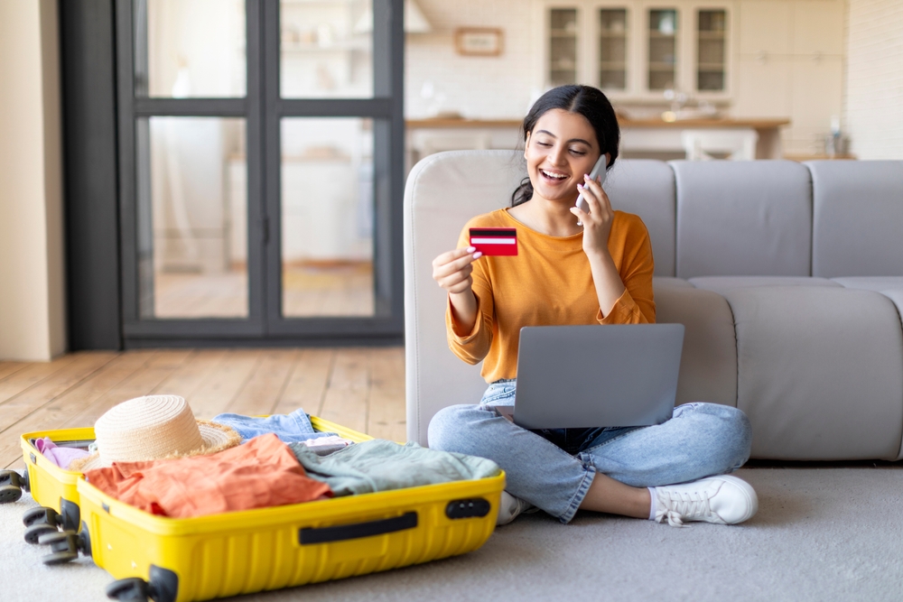 Happy young Indian woman about to go on a vacation making a purchase online with her card