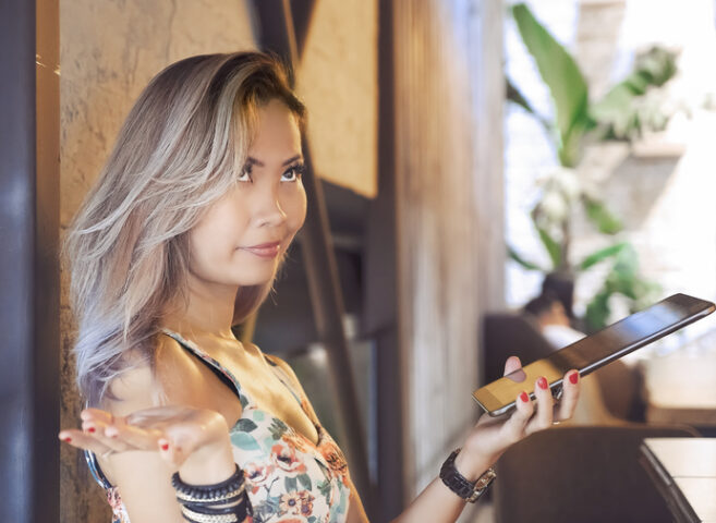 Woman shrugging and rolling her eyes working with digital tablet in a coffee shop