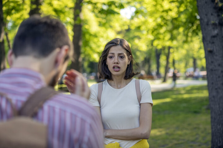 Handsome Young Man and His Beautiful Girlfriend are Having a Serious Debate Outdoors in the Public Park. Couple in Relationship is Going Through the Serious Problems and Difficulties. They are Yelling at Each Other.