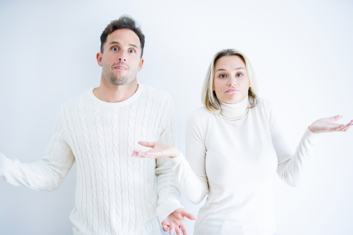 Couple with their hands up questioning and looking confused