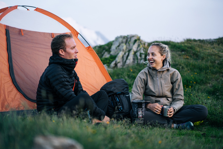 Friends relax outside tent at sunrise