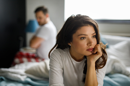 Sad couple sitting on bed after having a quarrel