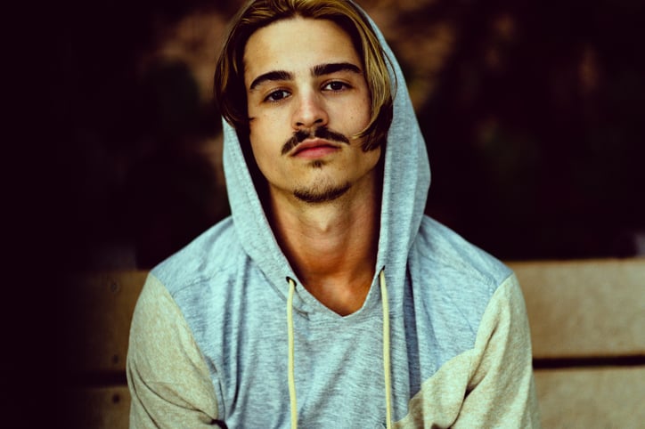 Moody and handsome young millennial age guy wearing a hoodie sweatshirt