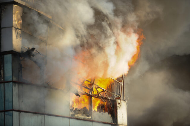 Fire and smoke engulf a metal and glass building
