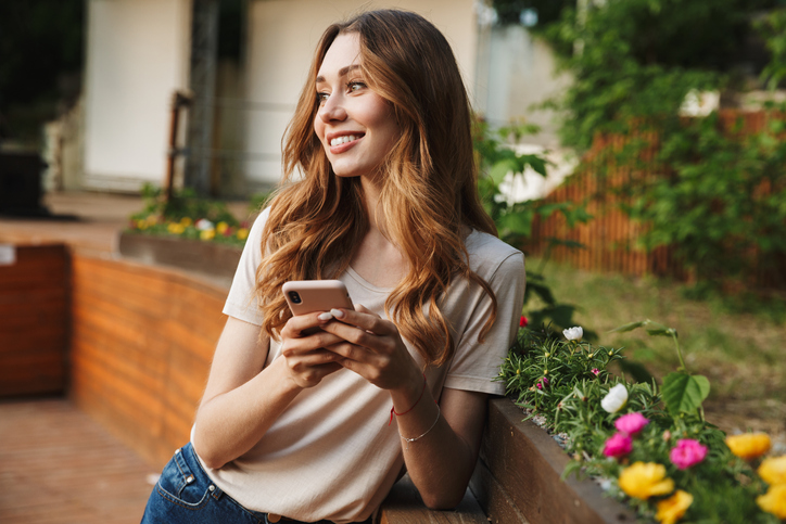 Young woman smiling holding her phone and texting