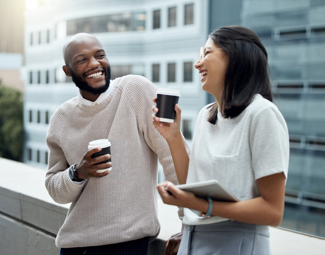 Shot of two businesspeople drinking coffee together outside an office