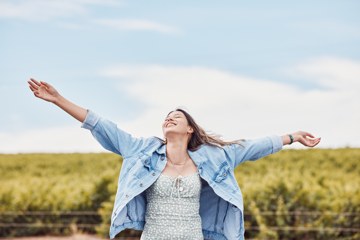 Happy woman smiling and enjoying freedom in nature with her hands in the air.