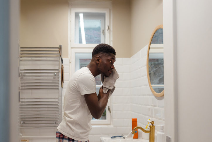 Photo of a young man washing his face in a bathroom