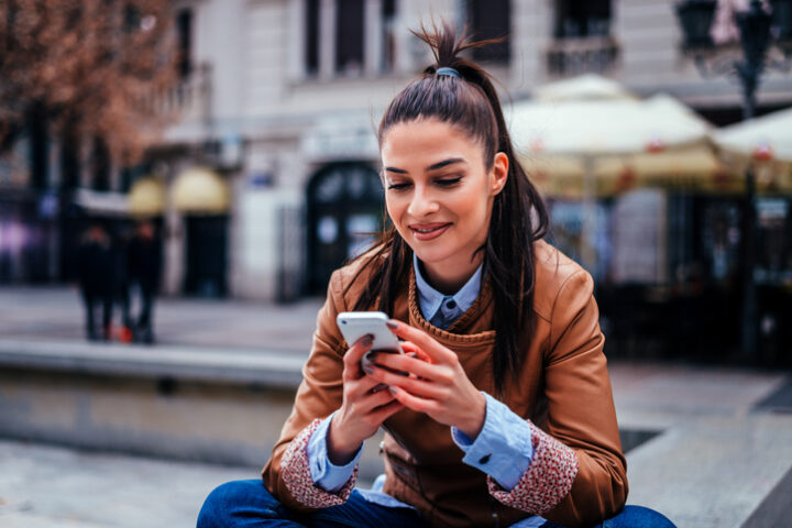Young woman smiling looking at her phone and texting