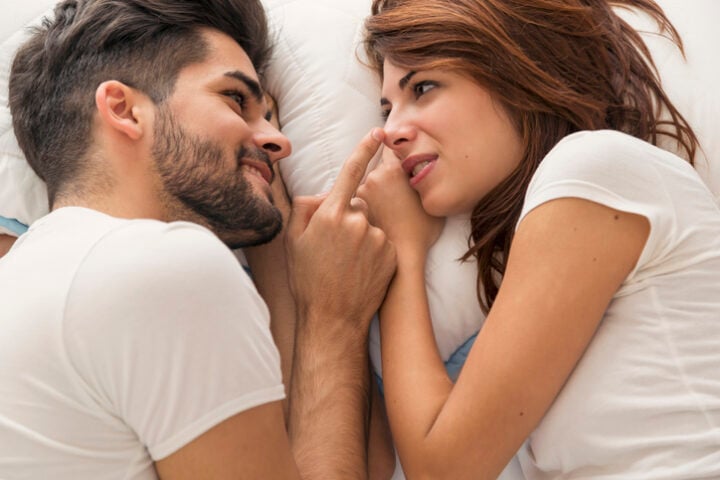 Top view of a couple in love lying in bed next to each other, resting and cuddling