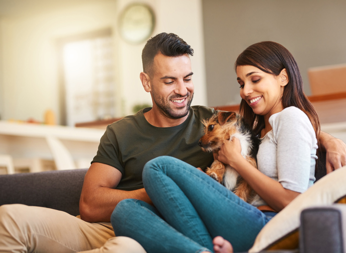 Shot of an affectionate young couple in love relaxing with their pet dog at home