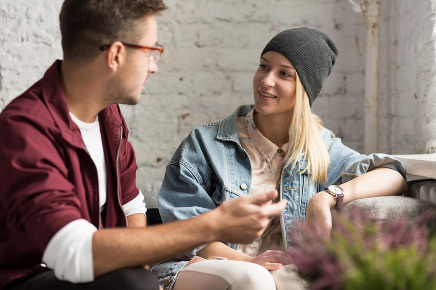 Young hipster couple talking in cozy cafe