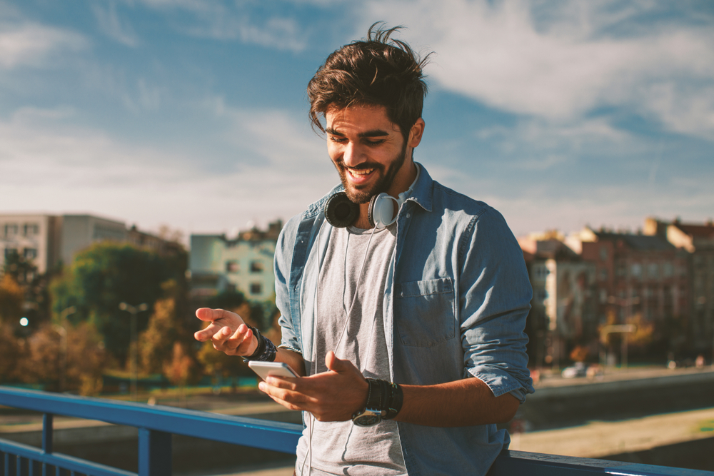 Young happy man using his smartphone in the city