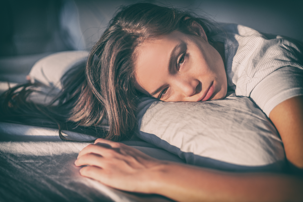 Tired stressed out woman lying in bed alone.
