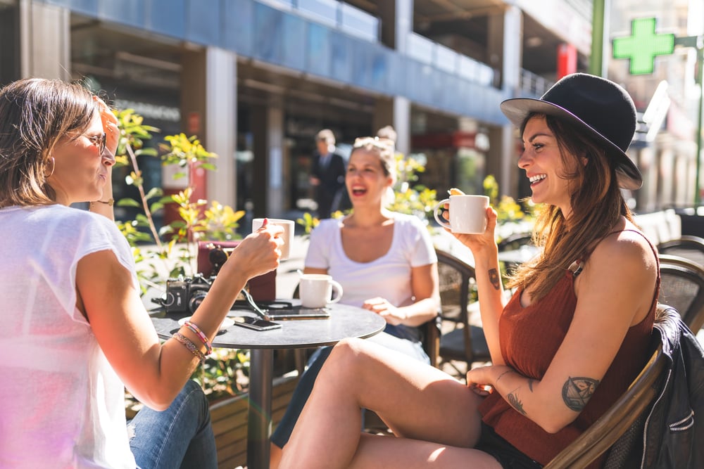 Three women and friends having a drink and talking outside
