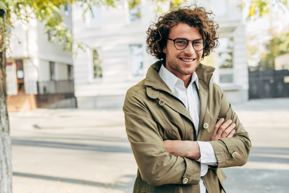 A young successful man walking alone and smiling outside. 