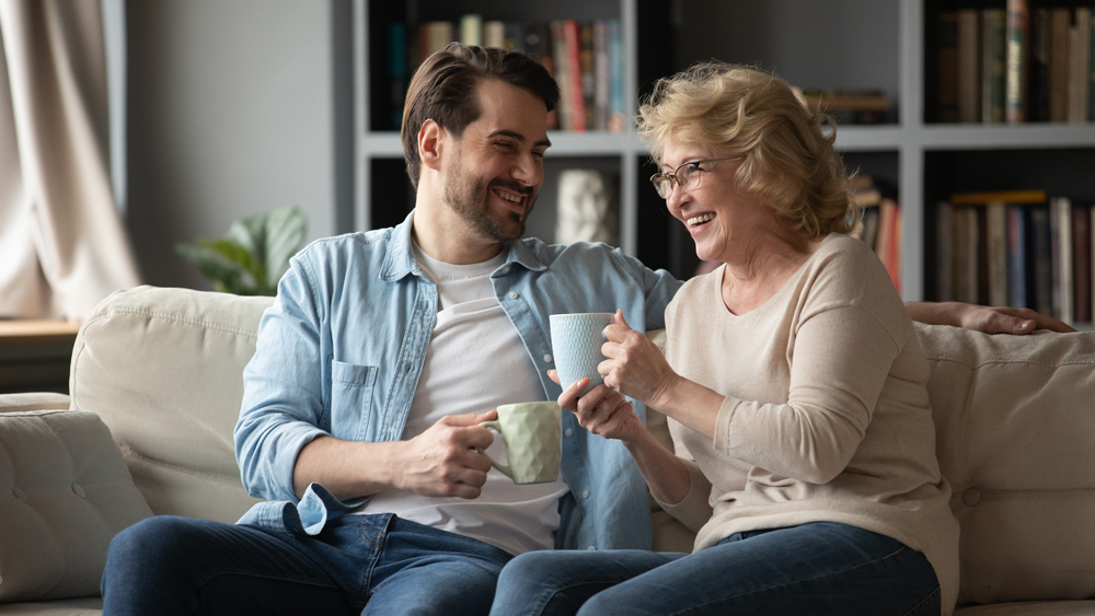A handsome young man telling funny jokes and stories to his mature mother
