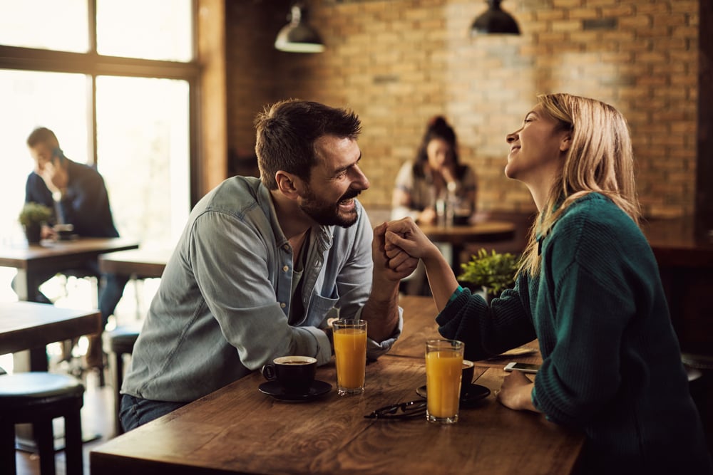 A happy man sitting at the bar and flirting with a laughing woman