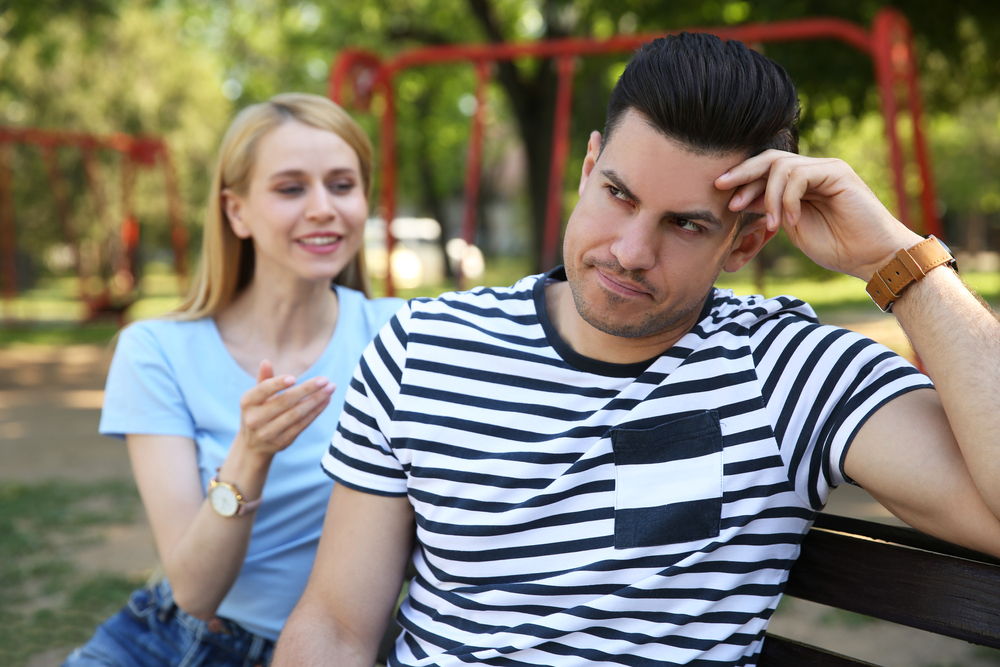 Displeased man ignoring his girlfriend and turns his back to her