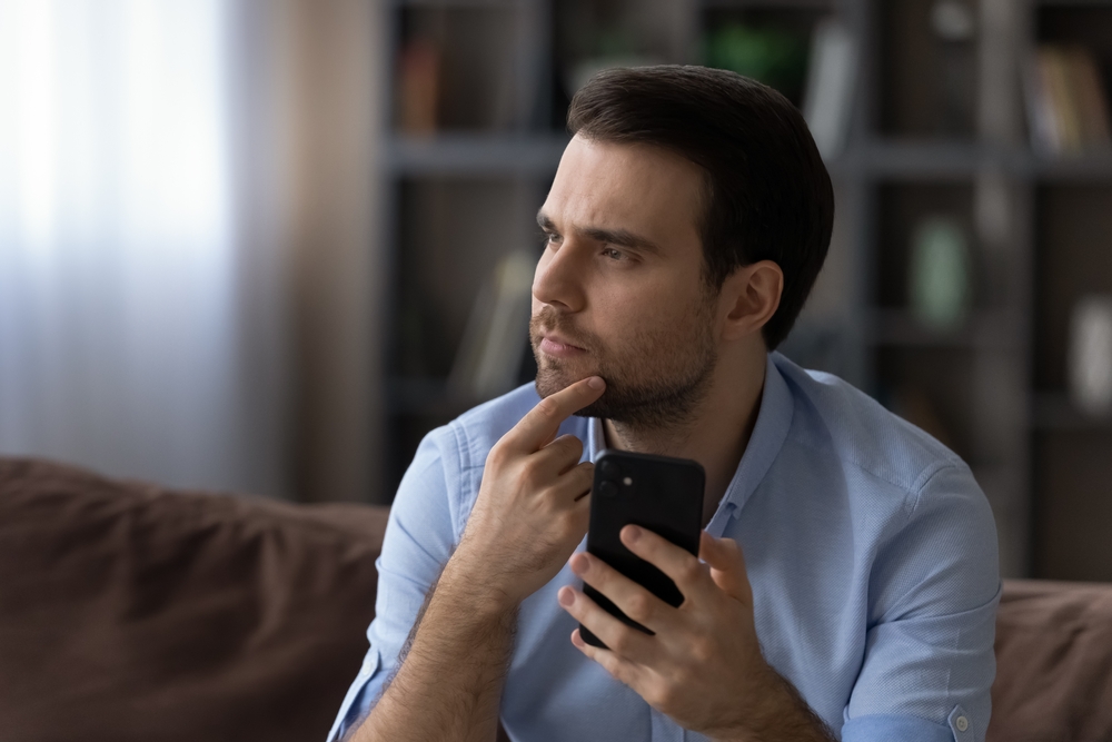 A thoughtful serious young man with his phone