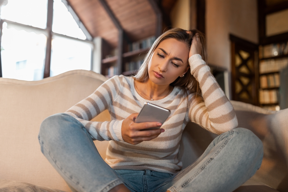 An upset young woman looking at her phone