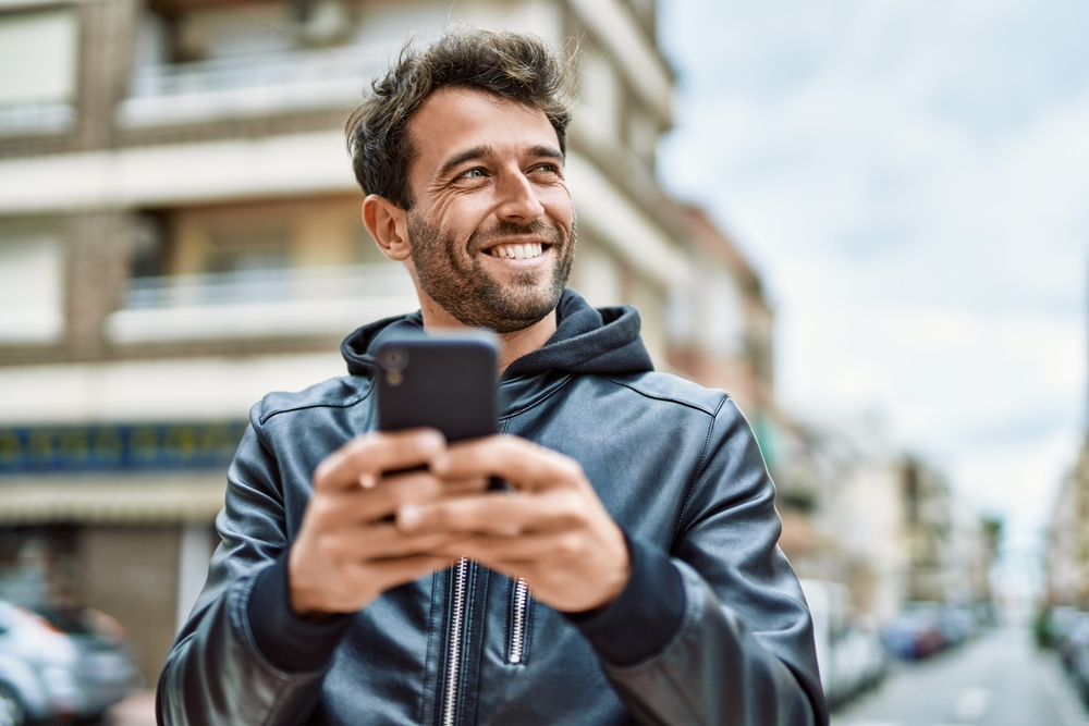 A handsome man smiling and using his phone