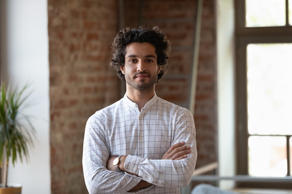 A young millennial man with curly hair smiling