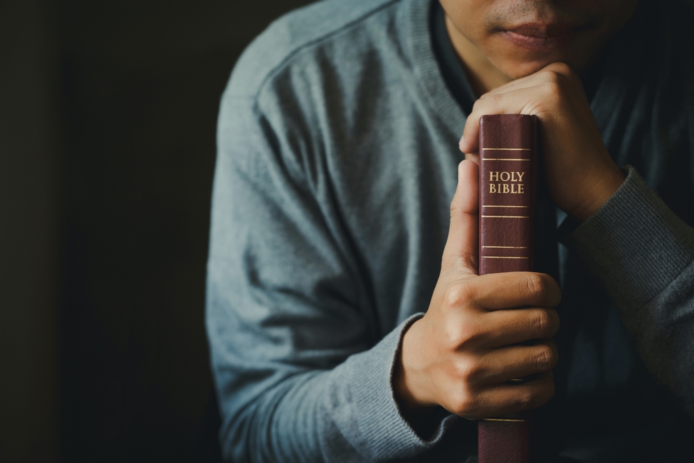 Man praying on the holy bible.