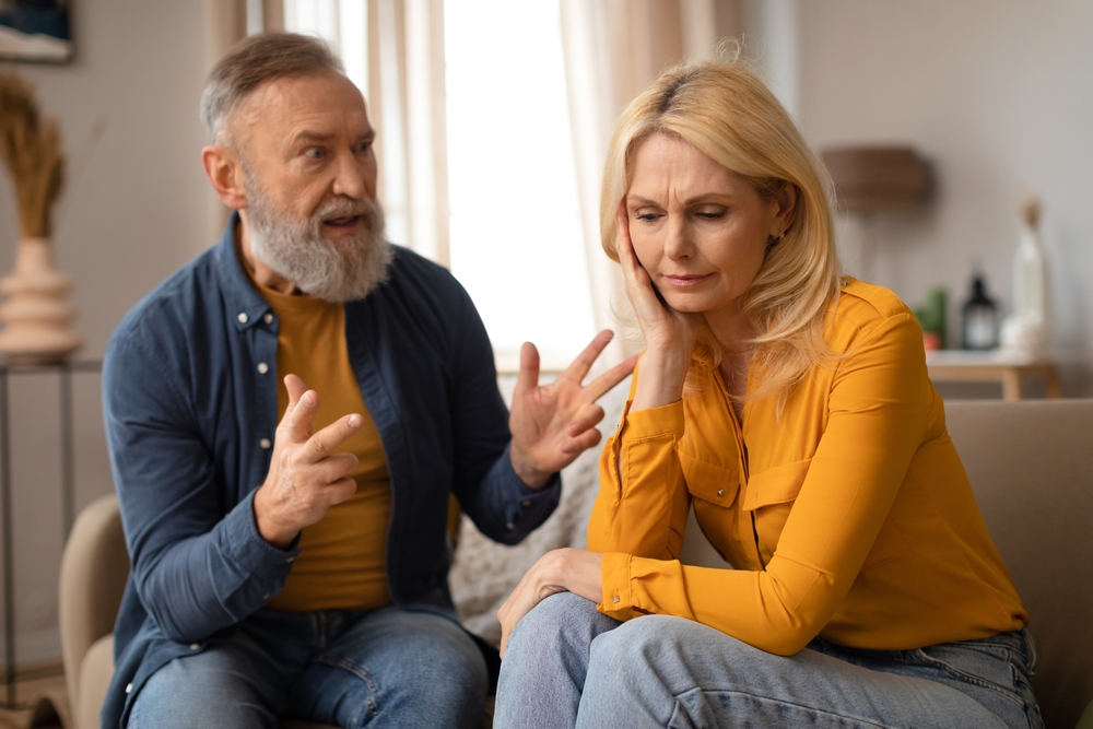 Unhappy couple having an argument, the man is raising his voice and the woman is quiet but sad