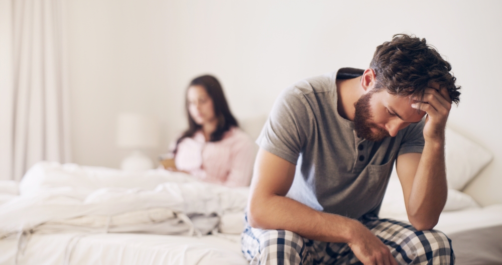 A tired couple arguing about sleeping in the same bed.